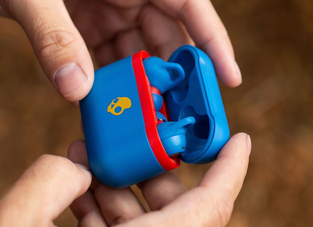 A person holds a case containing earbuds. 