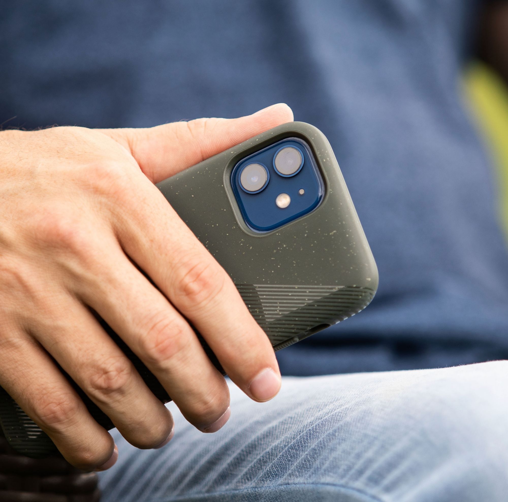 A person holds a phone at their side while sitting. 