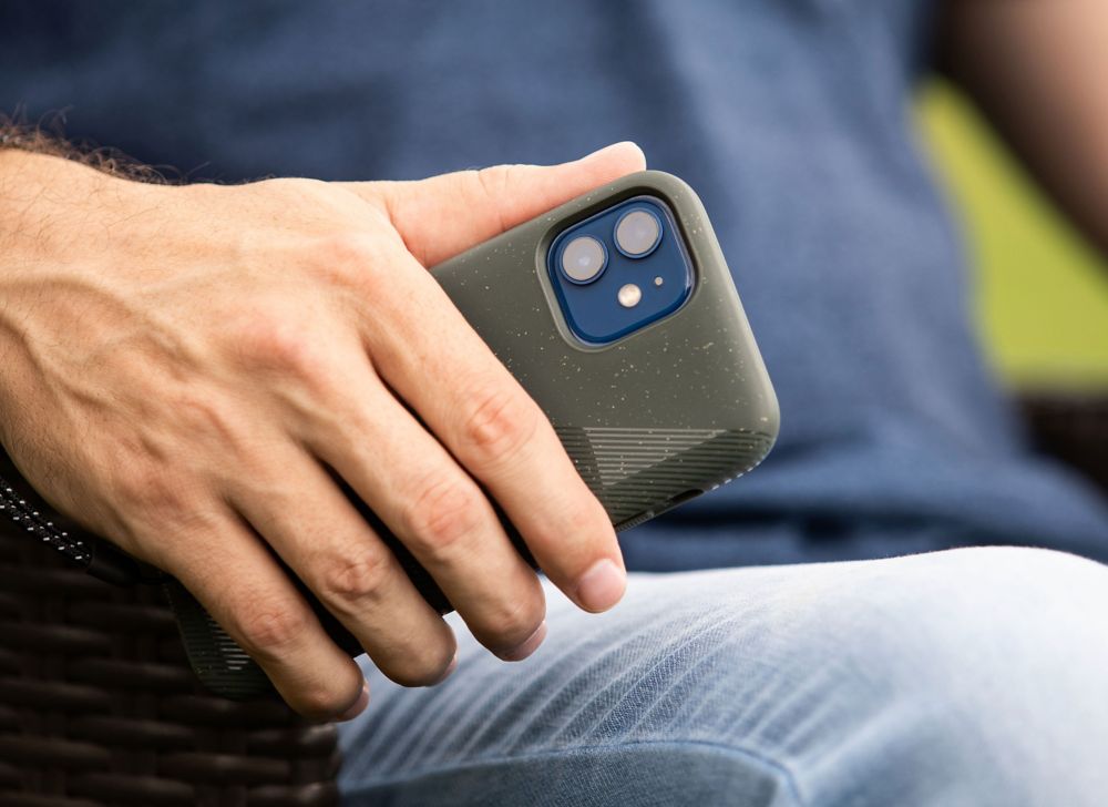 A person holds a smartphone at their side while sitting. 