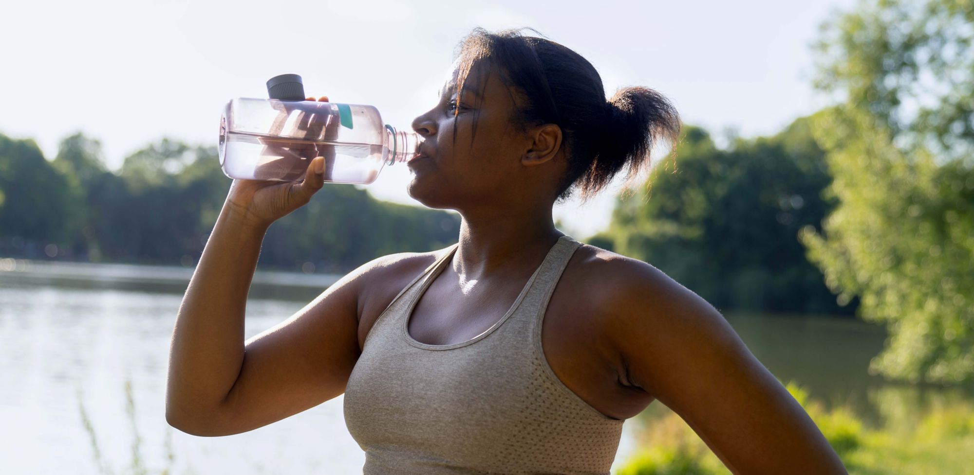 A person drinking water from a clear, reusable bottle made with Tritan. 