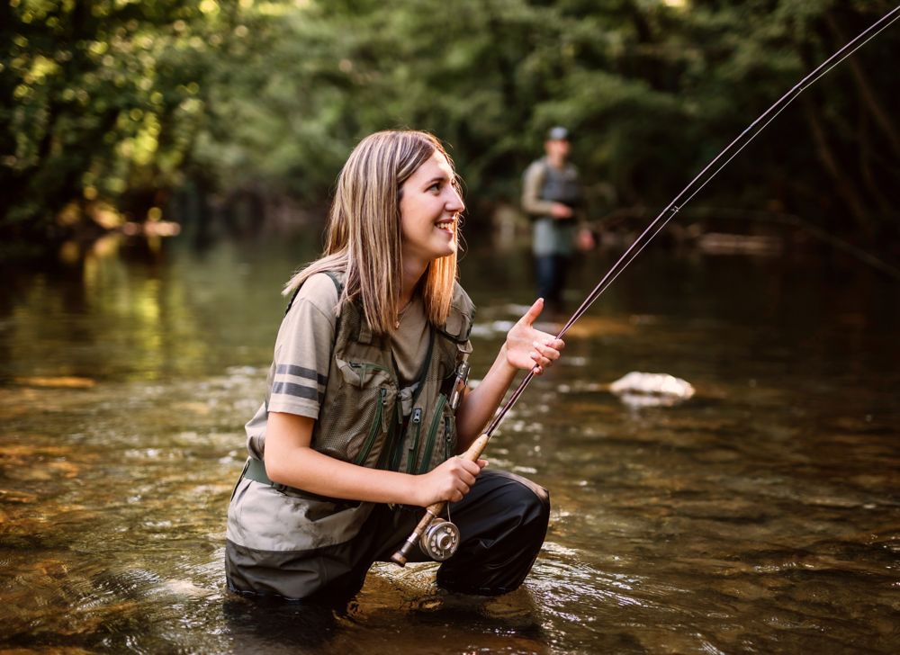 A person kneeling in the river fishing. 
