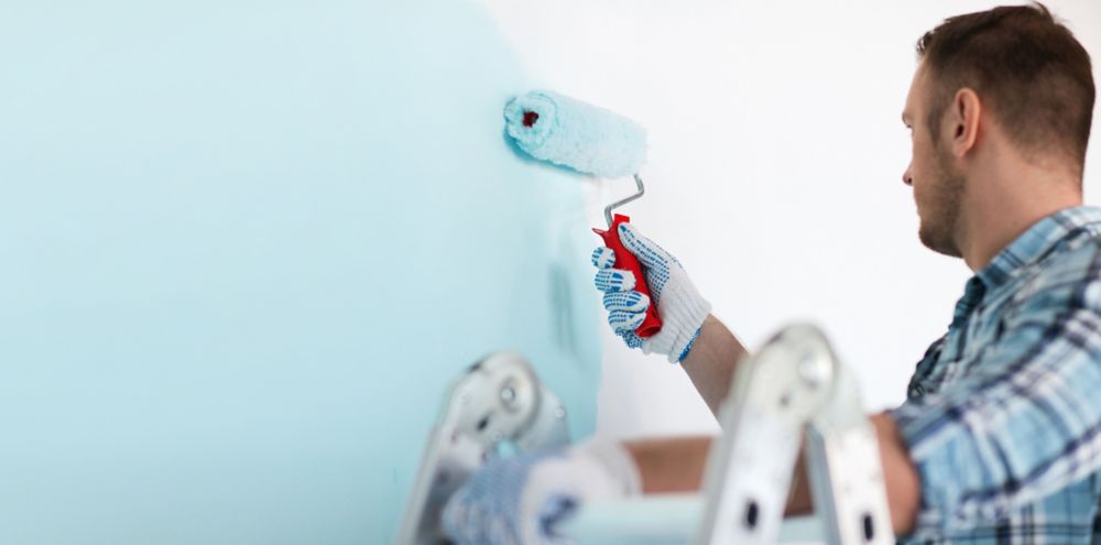 Person painting white wall blue 