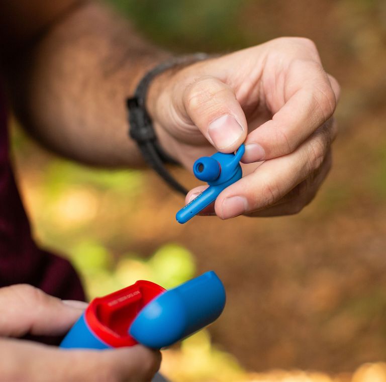 A person removes a blue earbud from its case. 