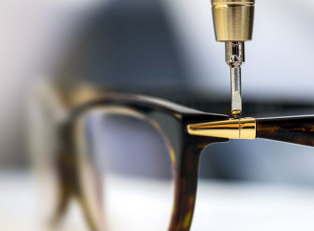 Close-up of a person tightening a screw on glasses. 