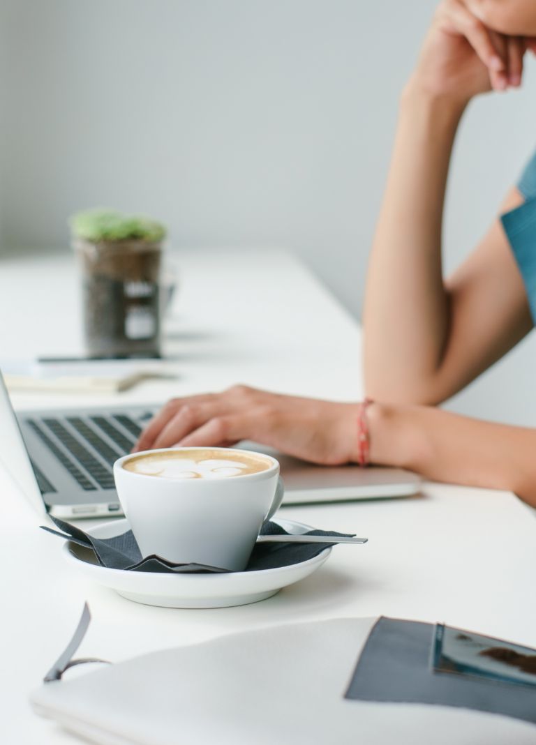 Person using laptop drinking coffee. 