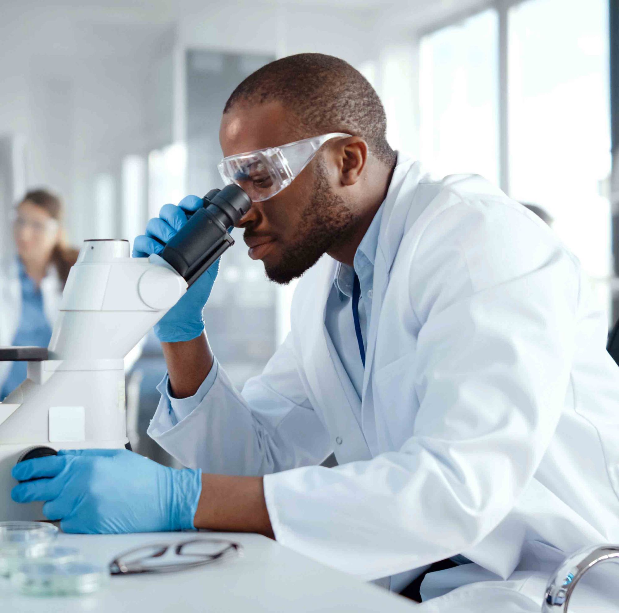 Employee in a lab using a microscope  
