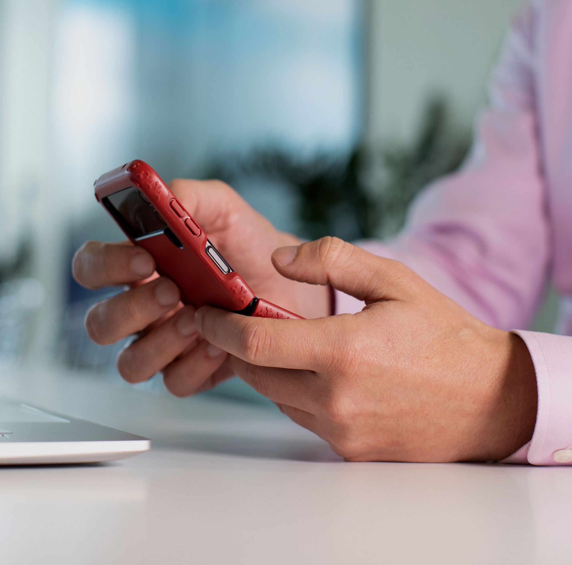 Close up of a phone in a red case being held. 