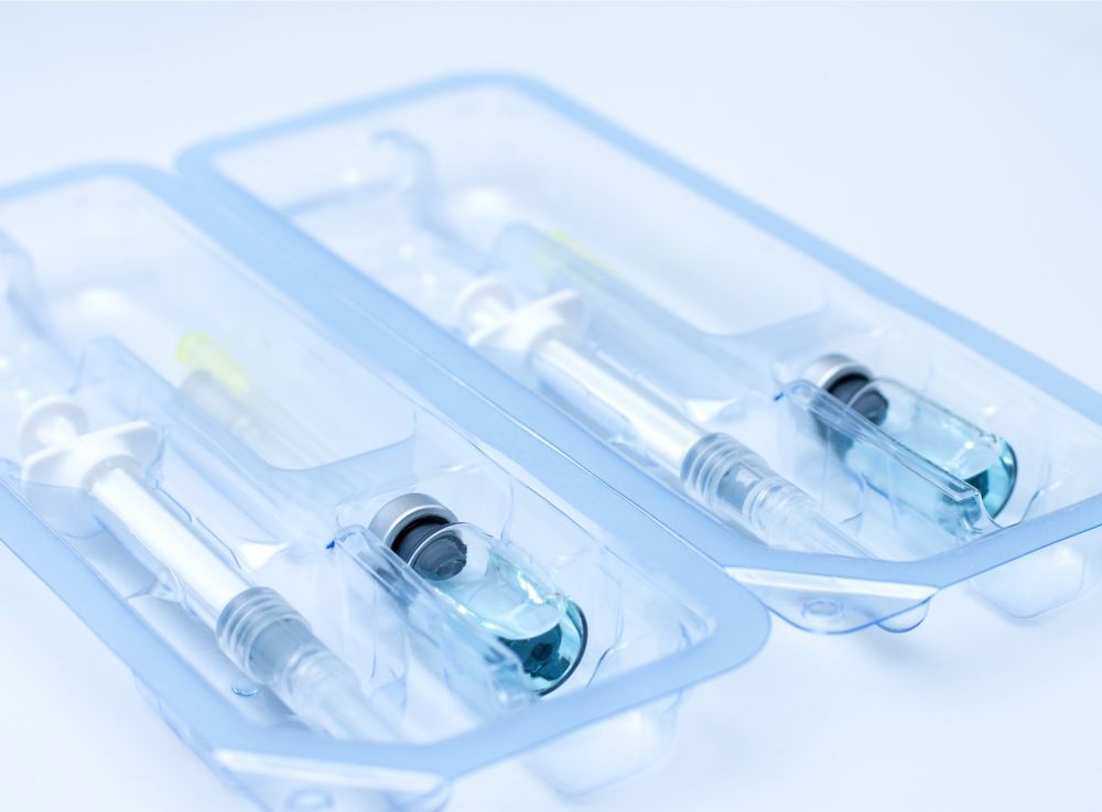 Clear plastic packaging that contains a syringe and a vial with clear liquid inside.  