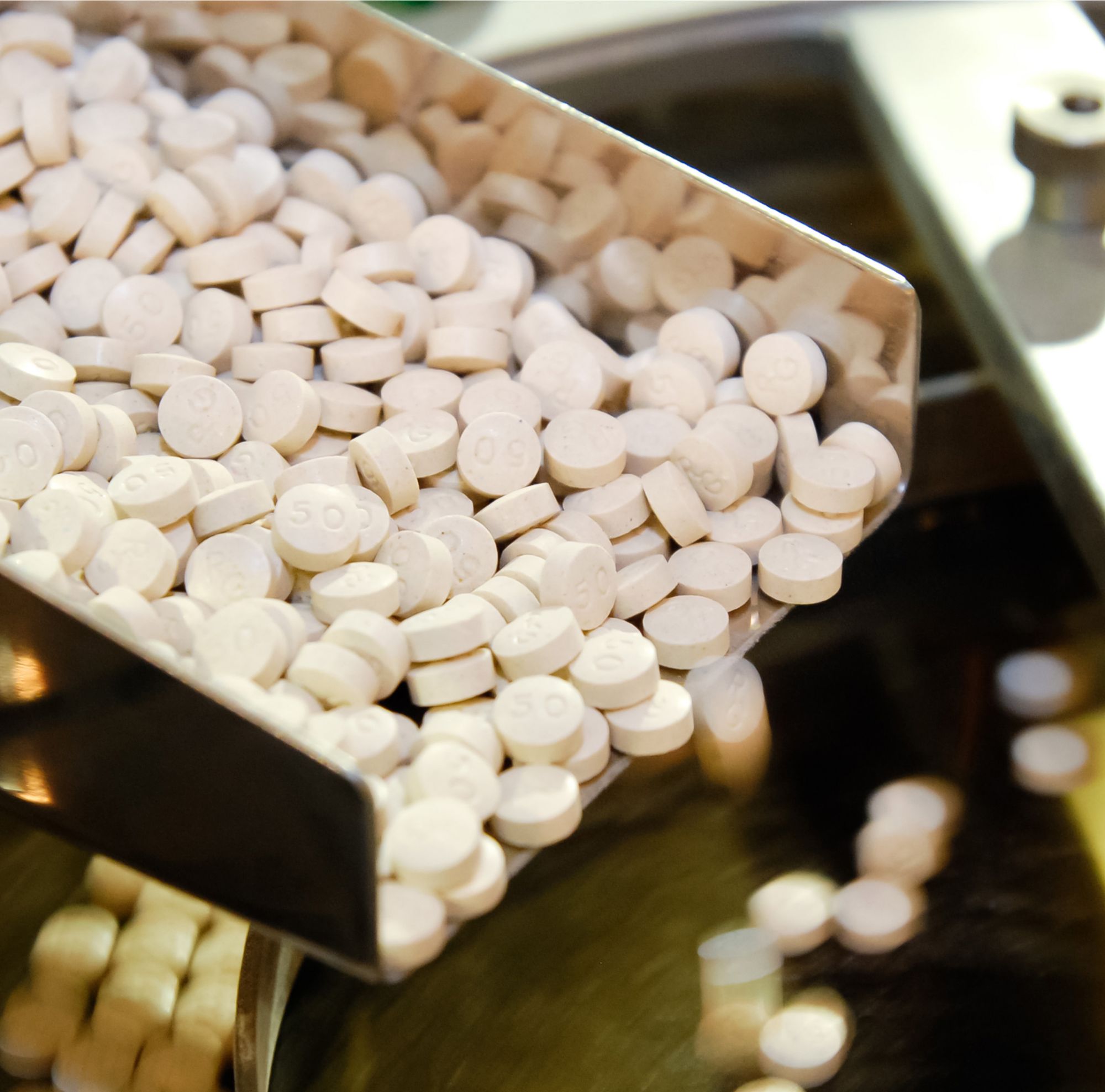 Round, pale-pink pills being produced. 