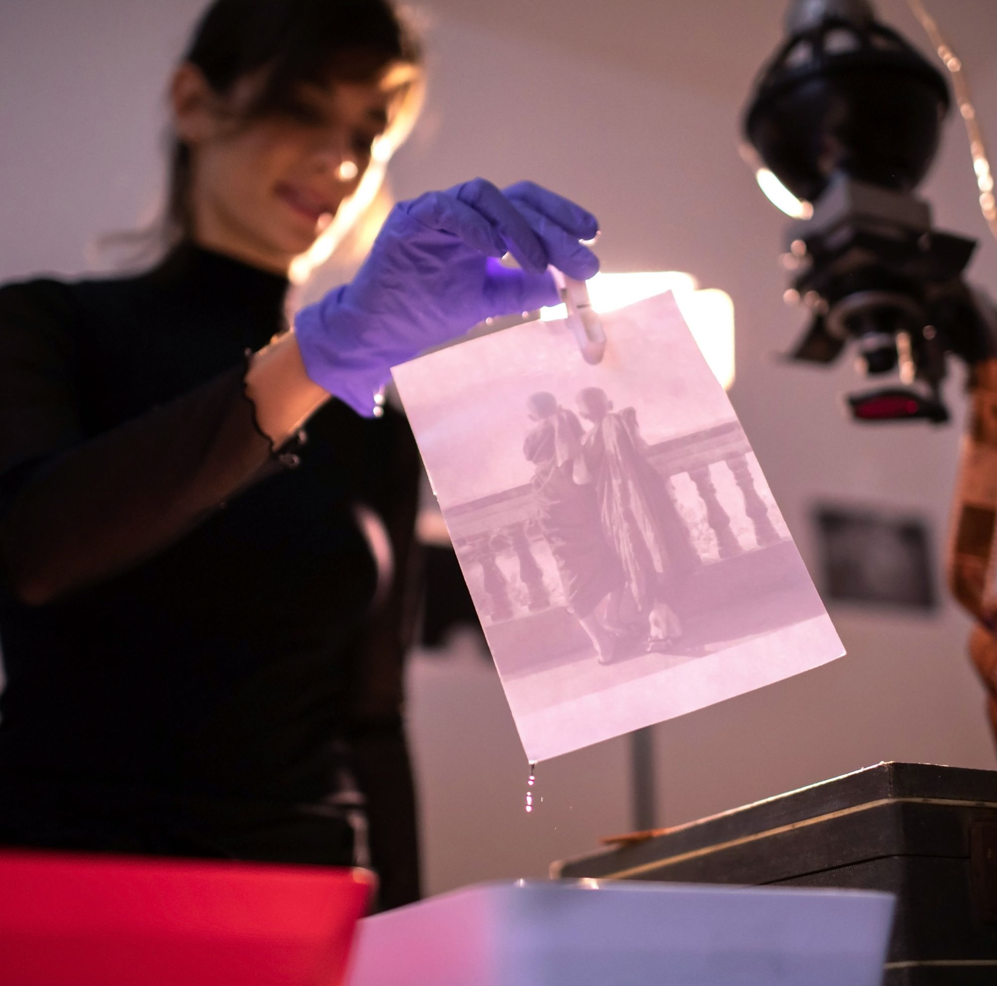 A woman develops a photograph in a darkroom. 