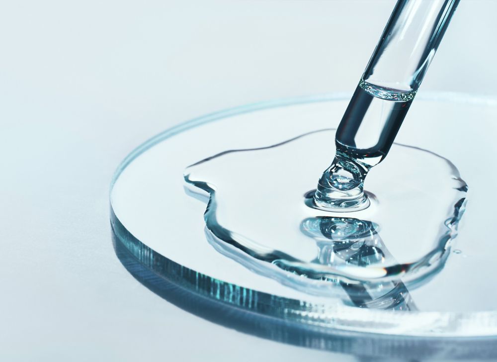 A glass pipette releases colorless liquid. 