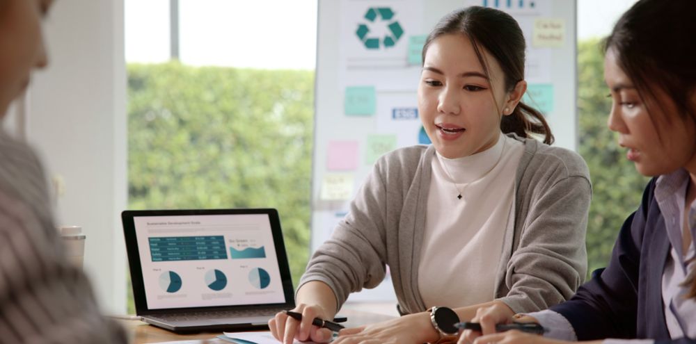 Three people sitting around a table and discussing recycling data. 
