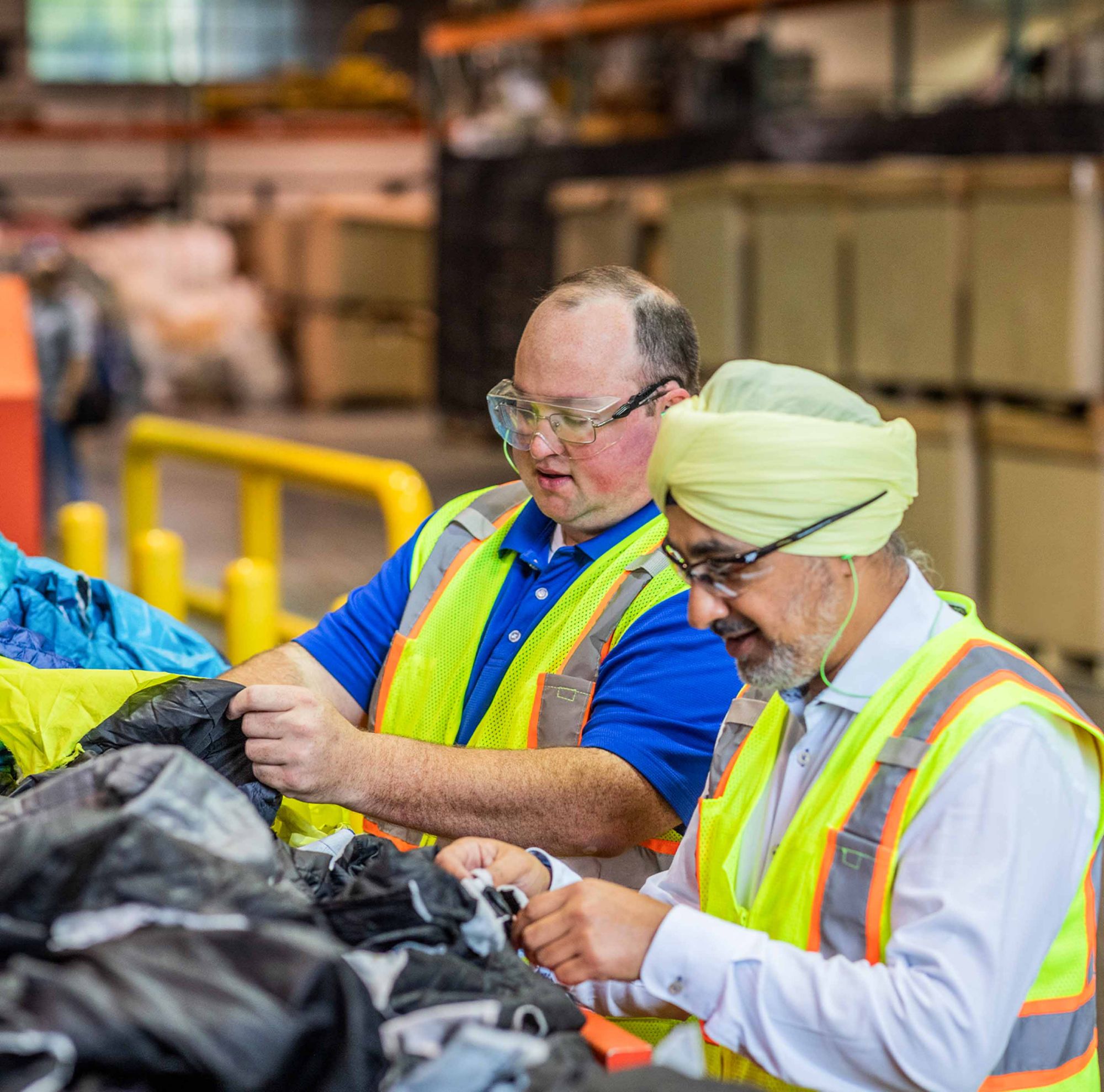 Two workers sorting plastic waste in a warehouse. 