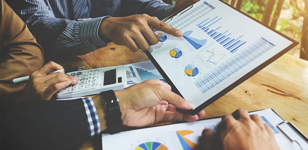 Employees point at graphs with discuss financial results. 