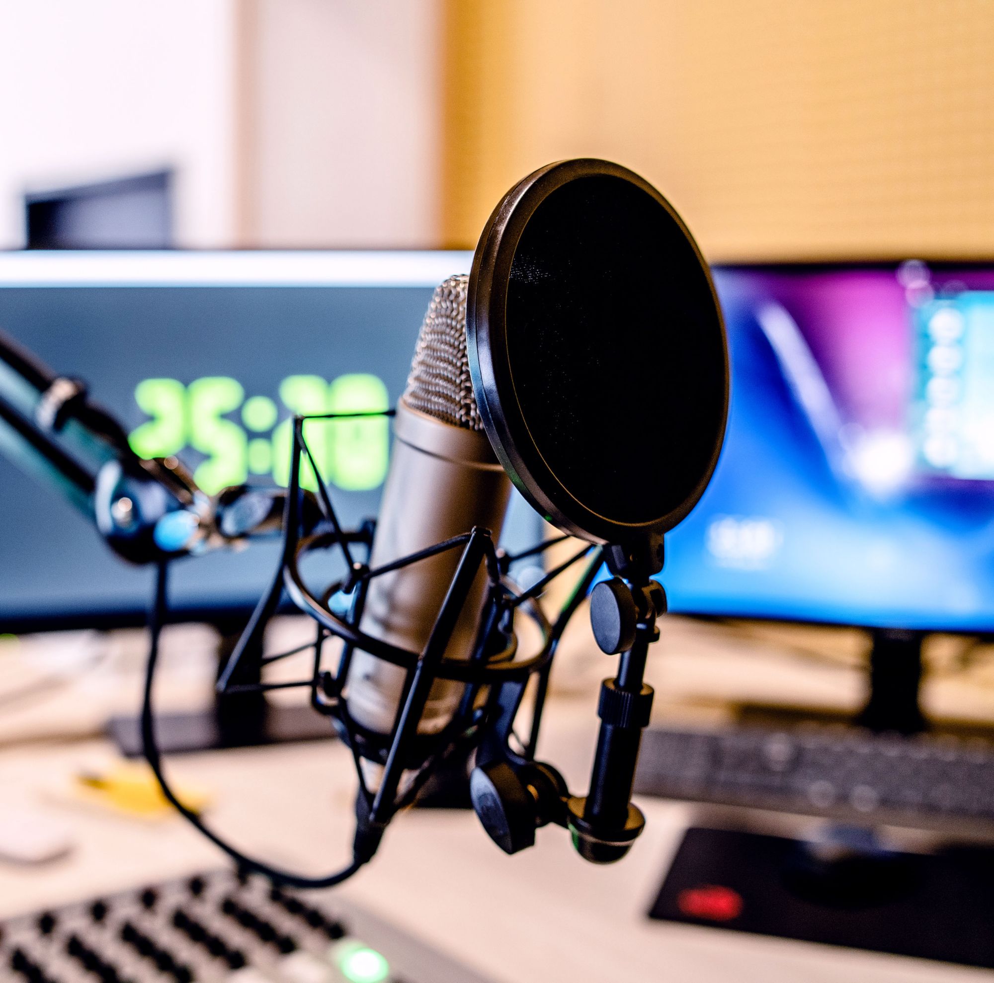 A microphone is set up in front of computer monitors. 