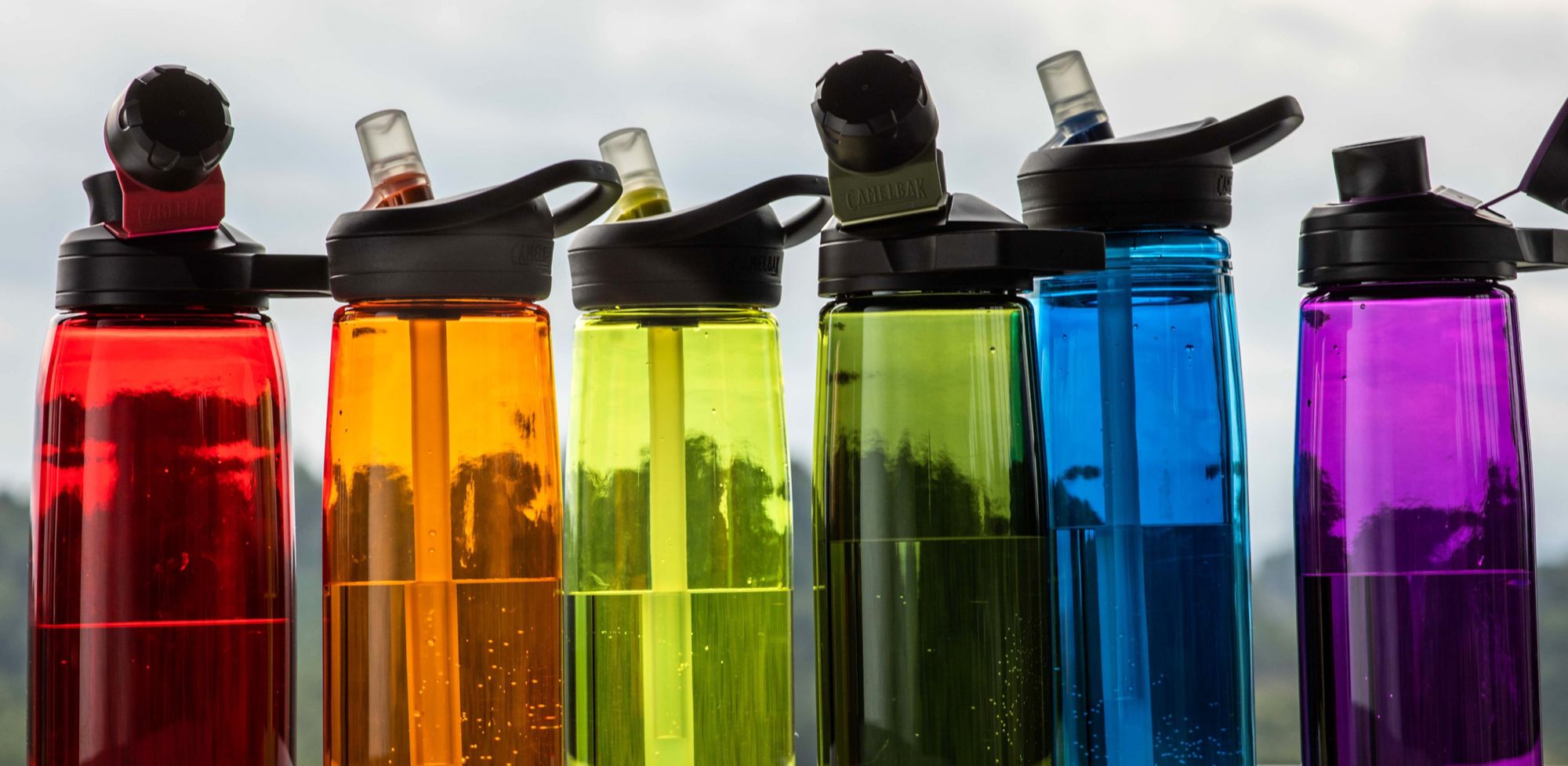 Red, orange, yellow, green, blue and purple water bottles lined up. 