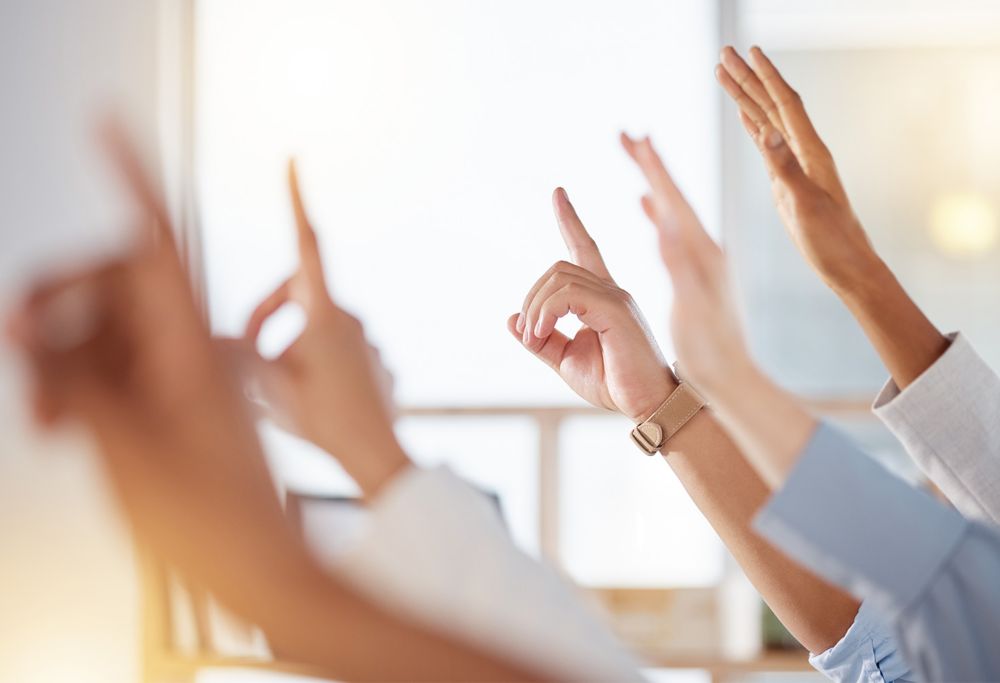 Five hands raised in a meeting room 