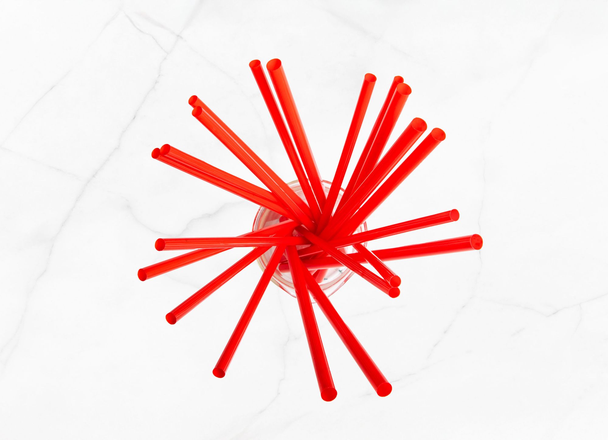 Multiple red straws are placed in a glass 