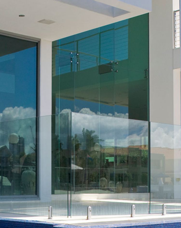 Modern home exterior with large glass doors opening to a pool. 