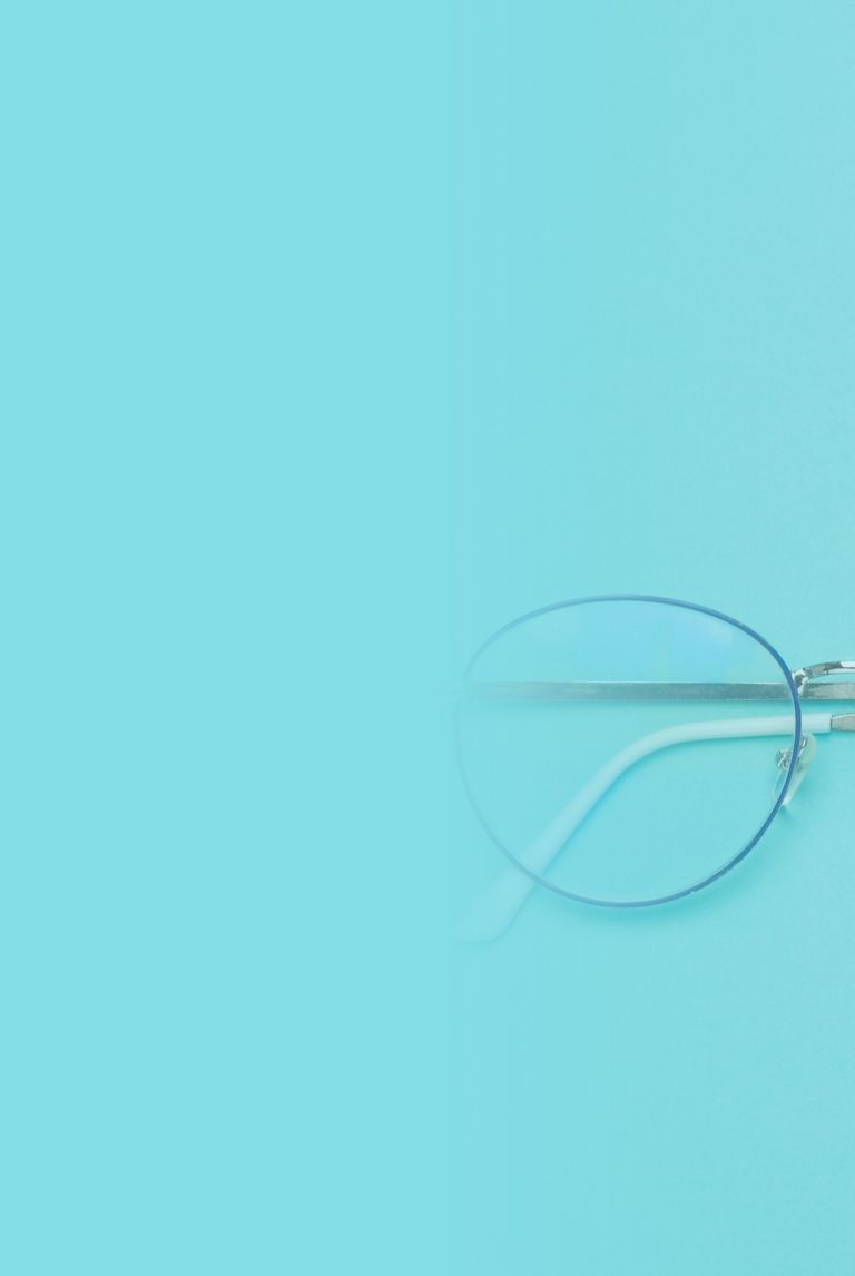 Wire-framed glasses resting on a light-blue surface. 