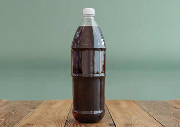 A large plastic bottle is filled with dark liquid. 
