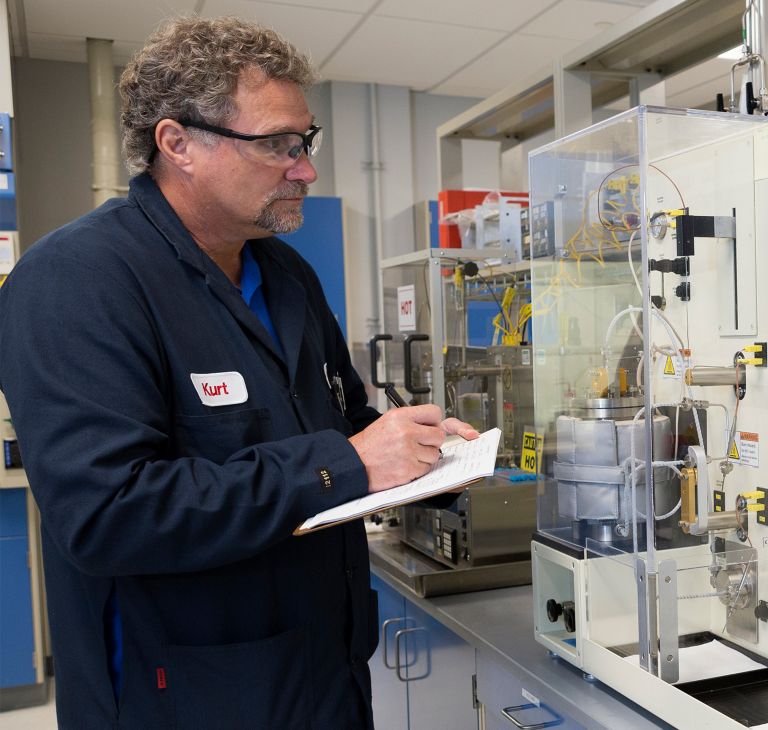 A man records data on paper he’s reading off a machine. 
