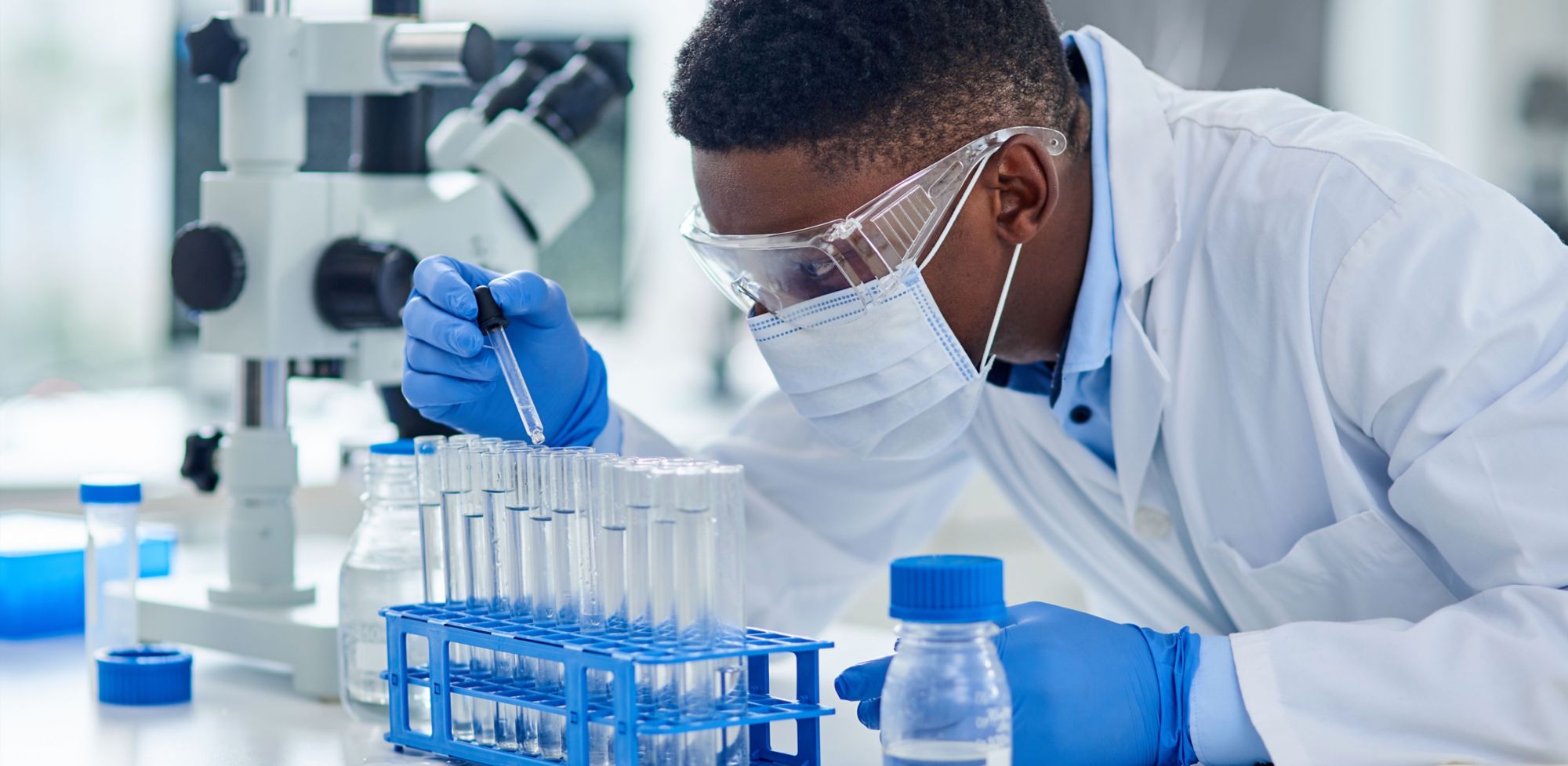 A scientist carefully pipettes clear liquid into test tubes. 