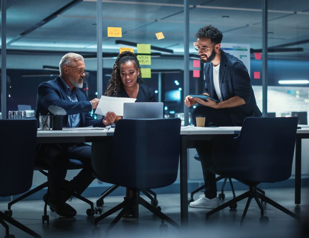 Three employees collaborating and looking at a document in the office. 