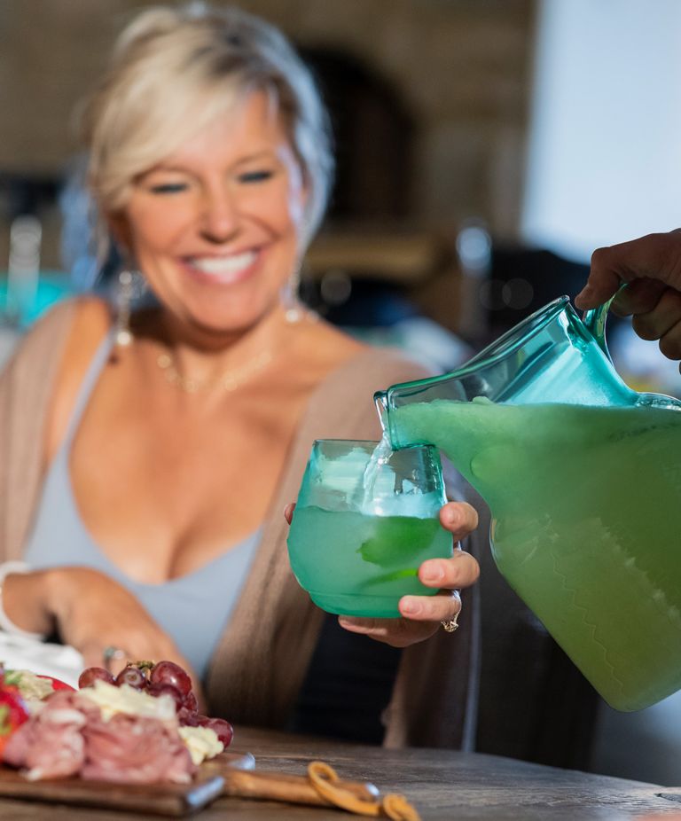 A woman is served an icy lemonade from a Tritan pitcher. 