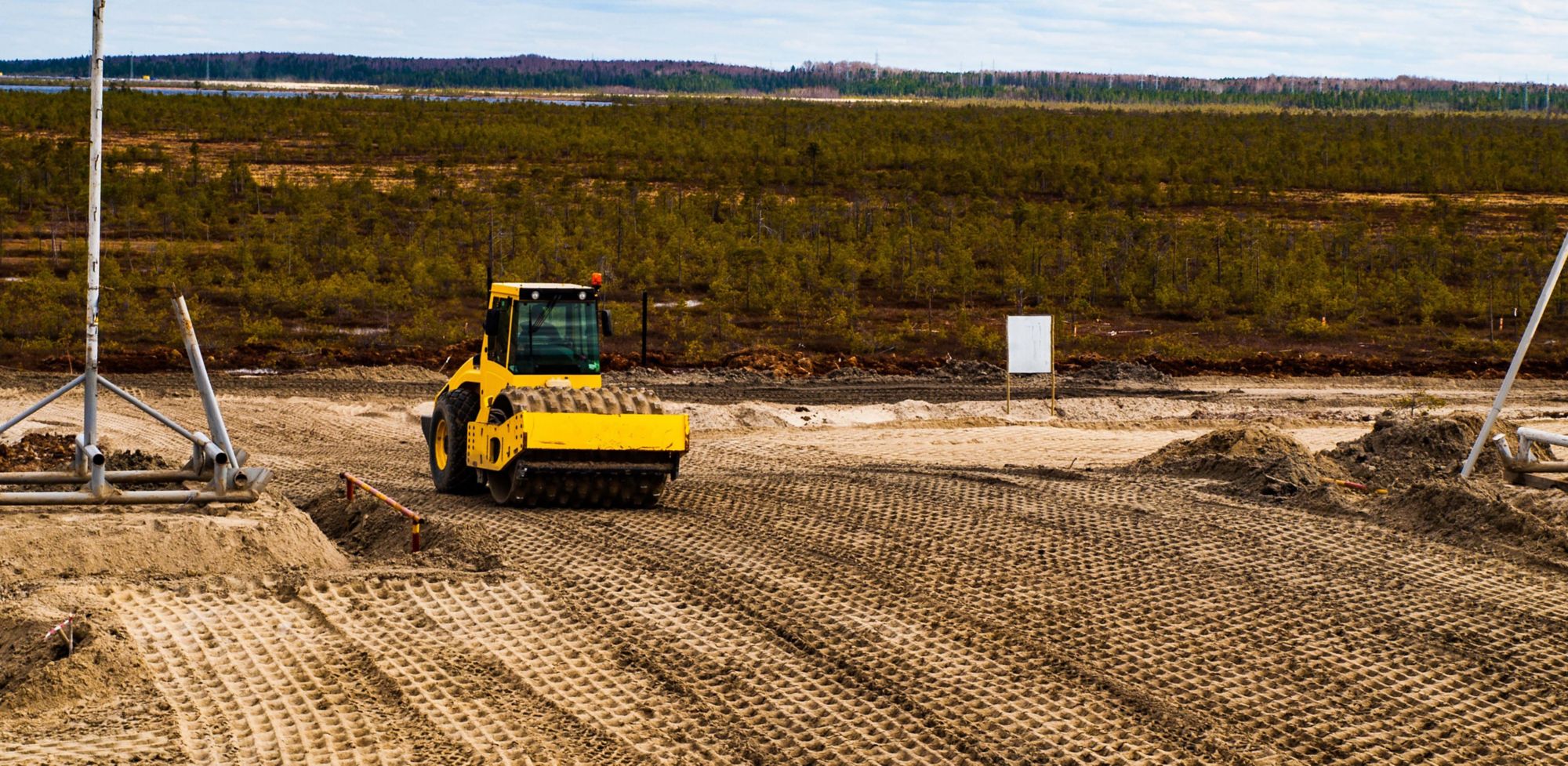 A construction roller drives over dirt.  