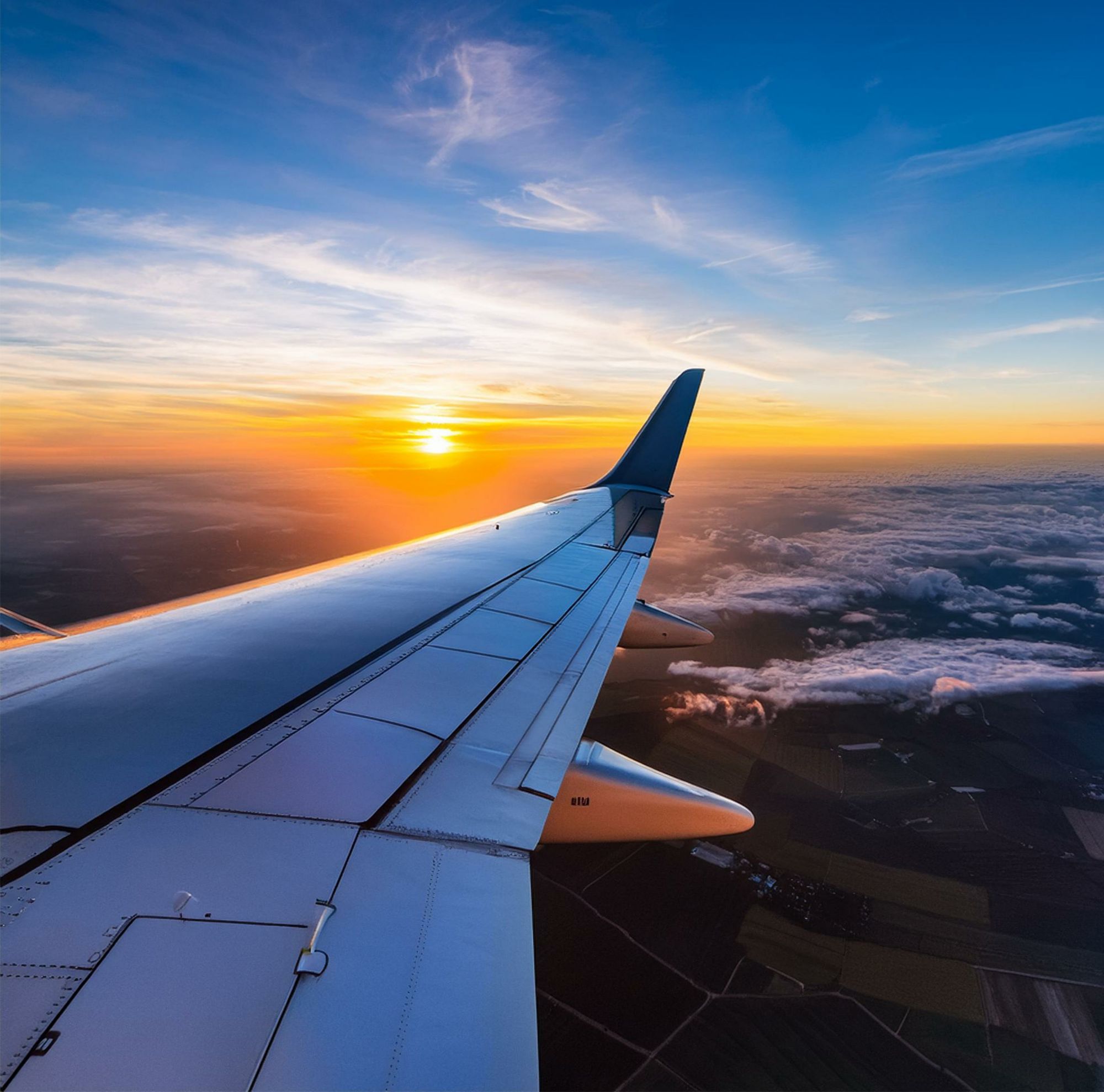 The wing of a plane is seen from the cabin window of the plane. 