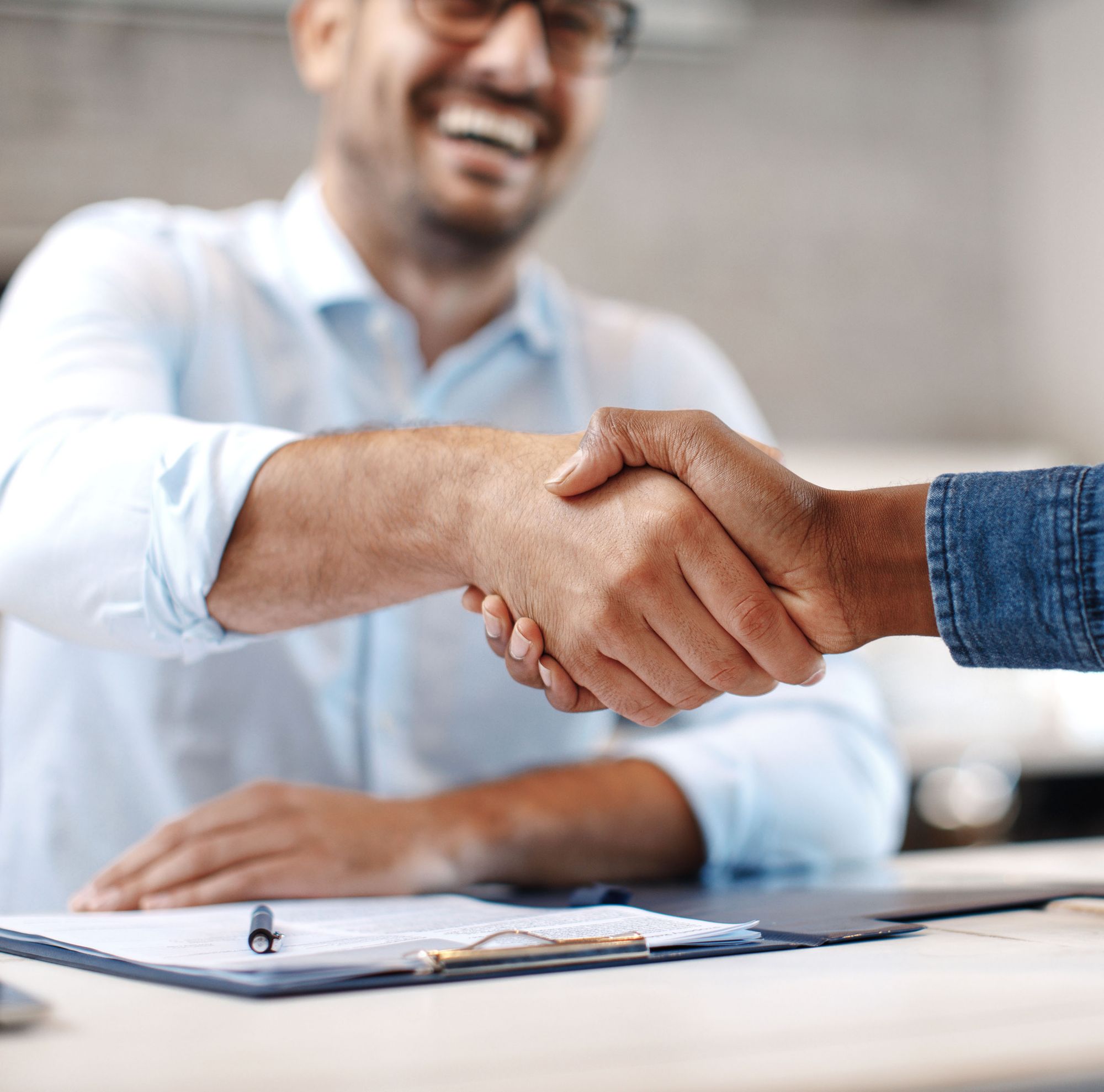 Two people smiling and shaking hands. 
