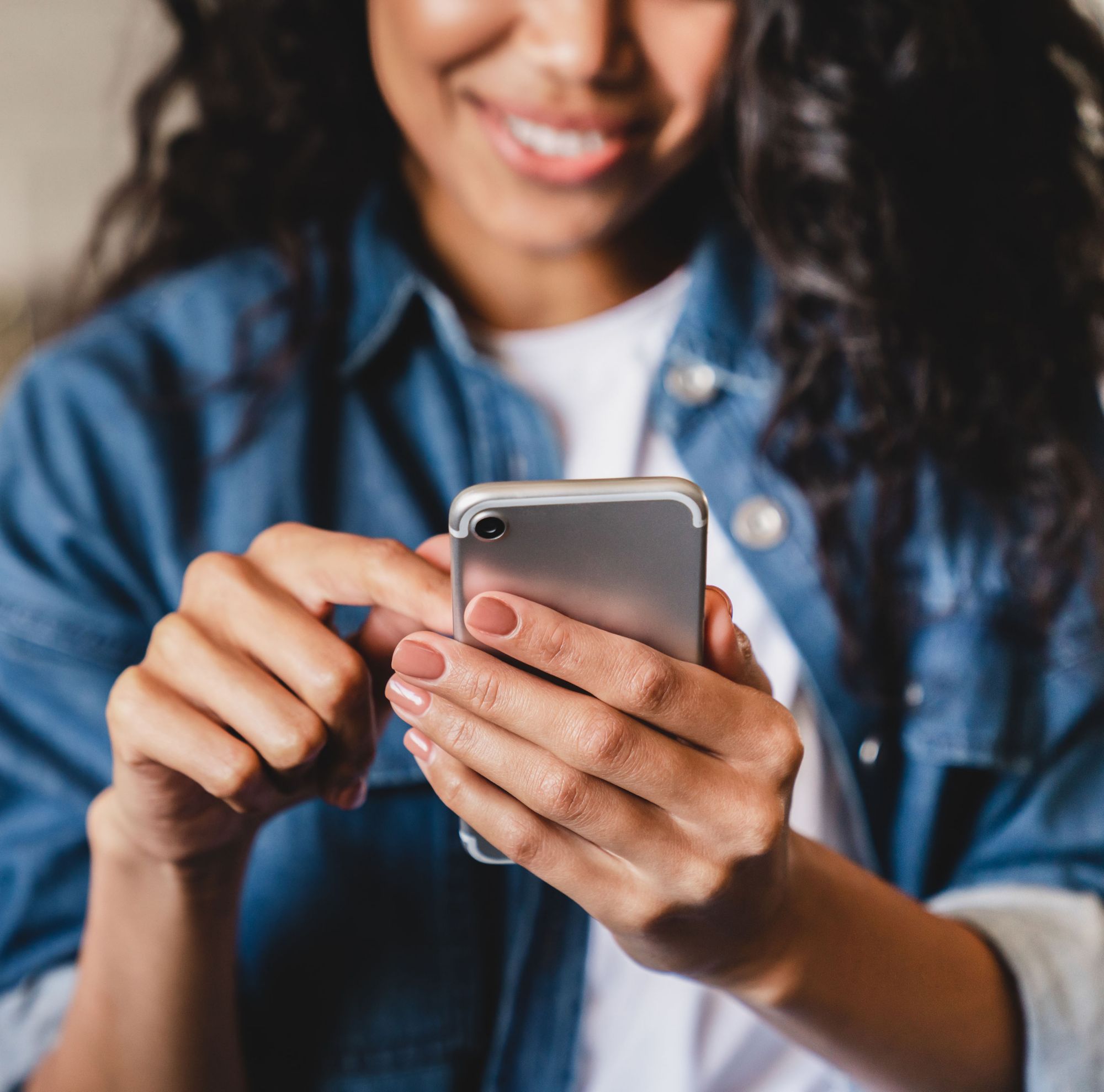 Woman smiling while scrolling on smartphone. 