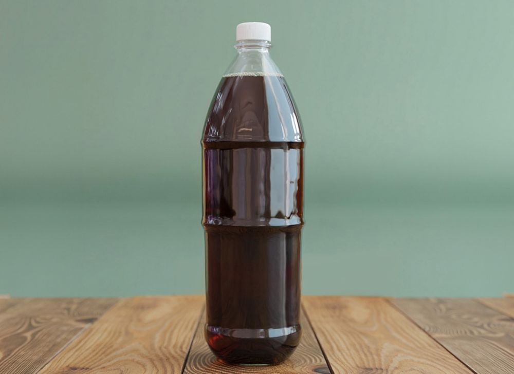 Clear refillable bottle made from Eastman PET Renew, filled with dark brown soda. 