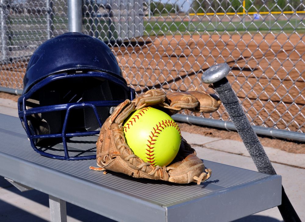 Softball helmet, bat, glove and ball on a bleacher 
