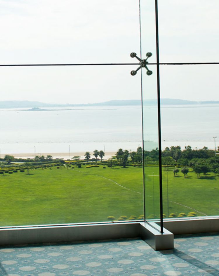Large glass windows overlooking a landscaped lawn and ocean view. 