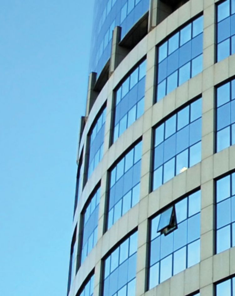 Curved high‑rise building with rows of blue windows against the sky. 