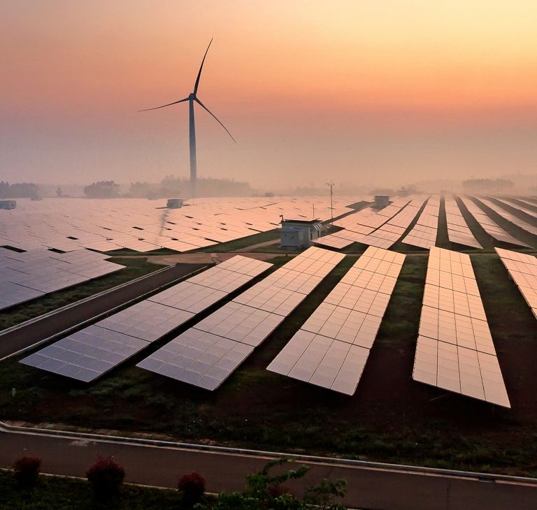 A field of solar panels and one wind turbine. 