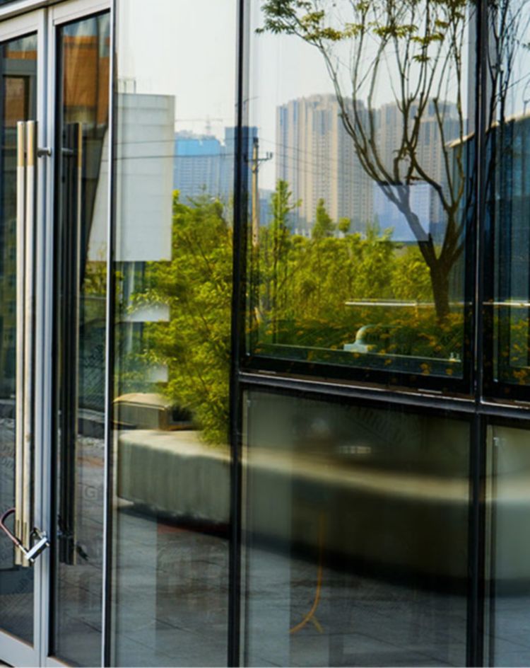 Modern commercial building with reflective glass walls and open exterior walkway. 