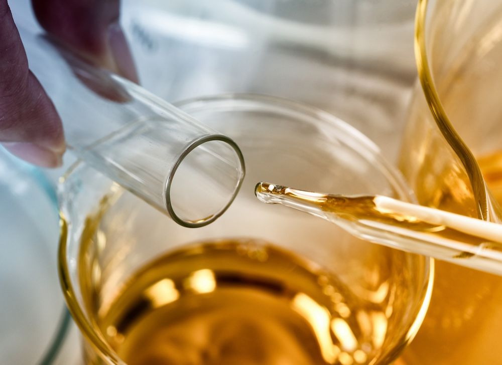 Someone inserts a dropper full of liquid into a vial. 