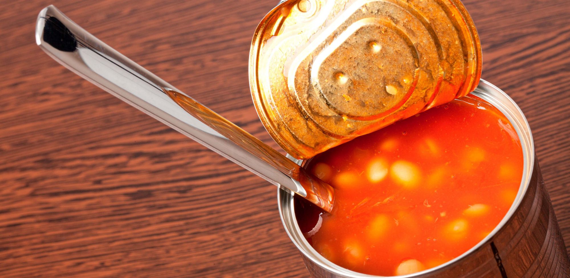 An opened can of beans with a spoon inside. 