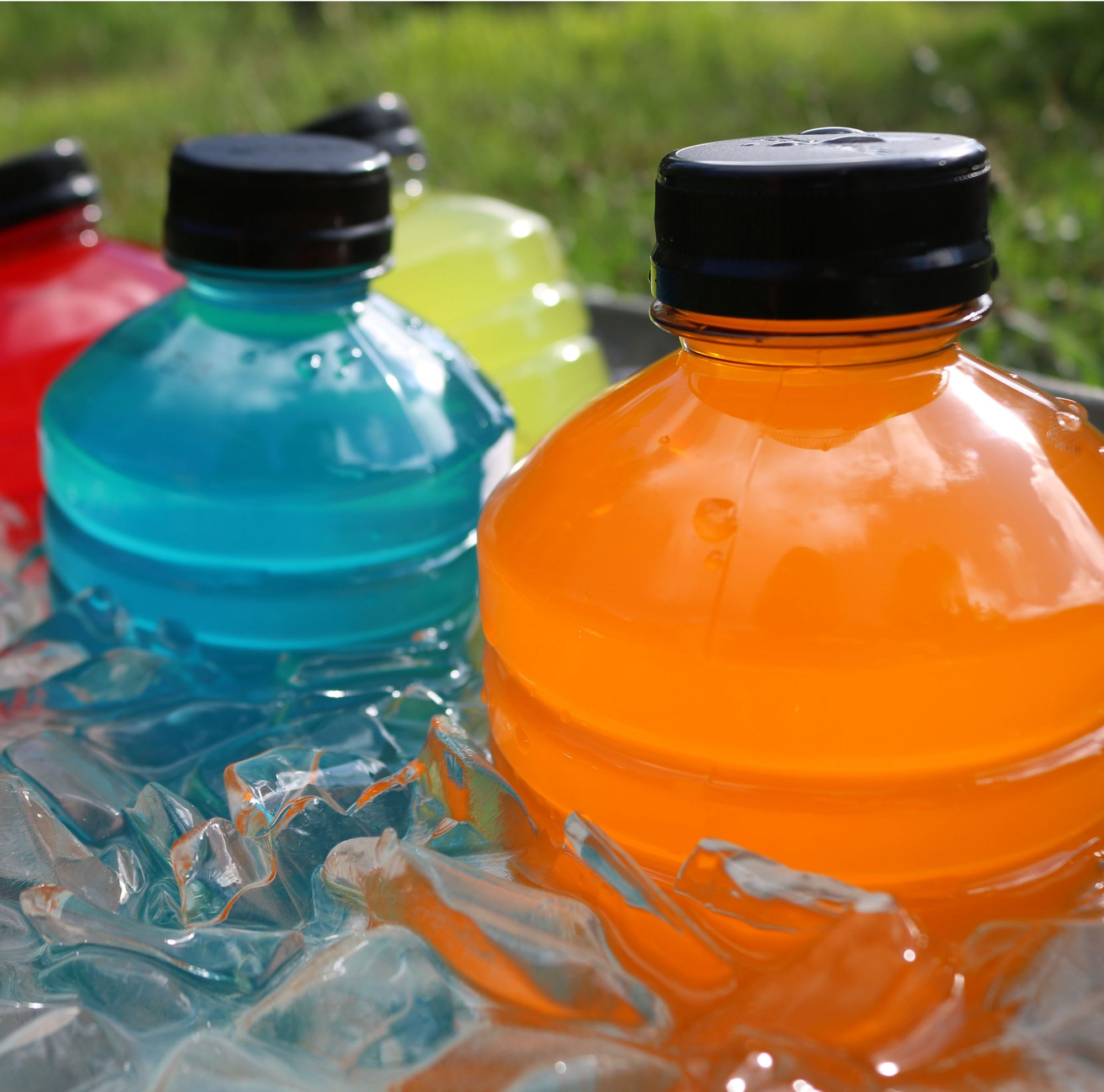 Various colors of sports drinks in an ice chest. 