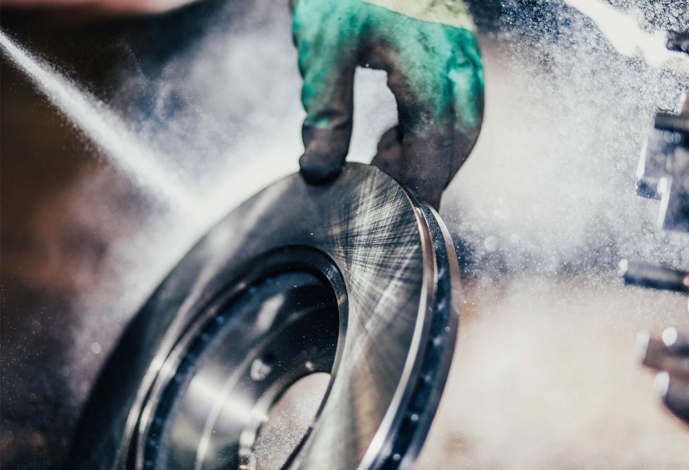 A person sprays aerosol material onto a round metal device. 