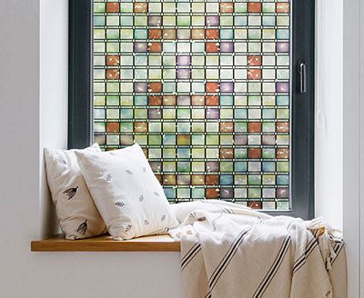 Cozy, private window nook showing the installed Stained Glass Atlantis film behind throw pillows.