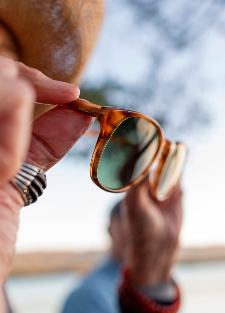 A person puts on a pair of eyeglasses made with Eastman materials. 