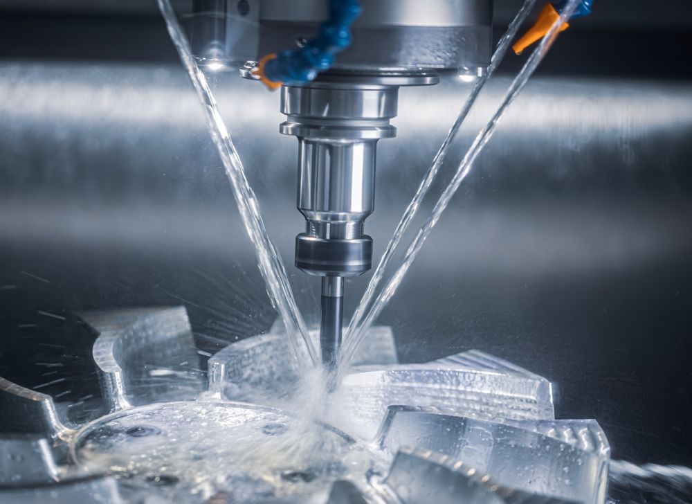 A machine drills into a material with metalworking fluids spraying. 