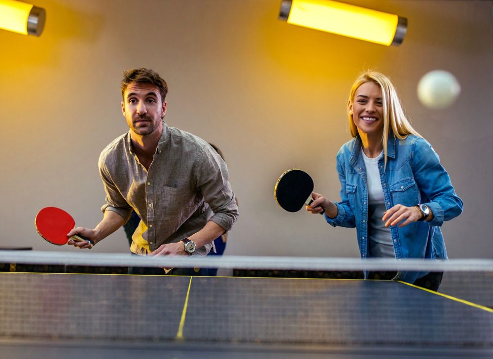 A man and woman playing doubles in a table tennis game. 