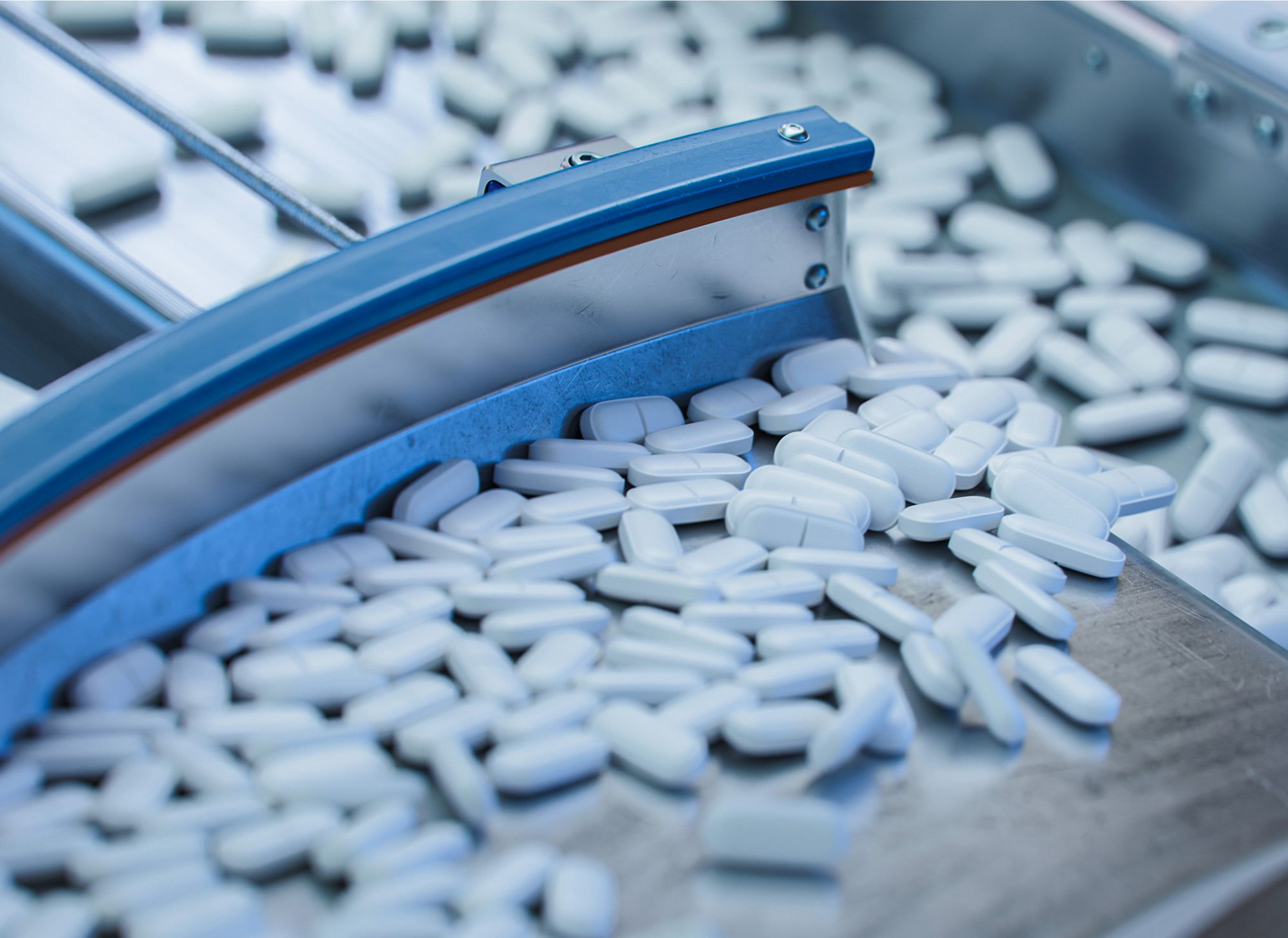A close-up of someone using tweezers to hold a round pill. 