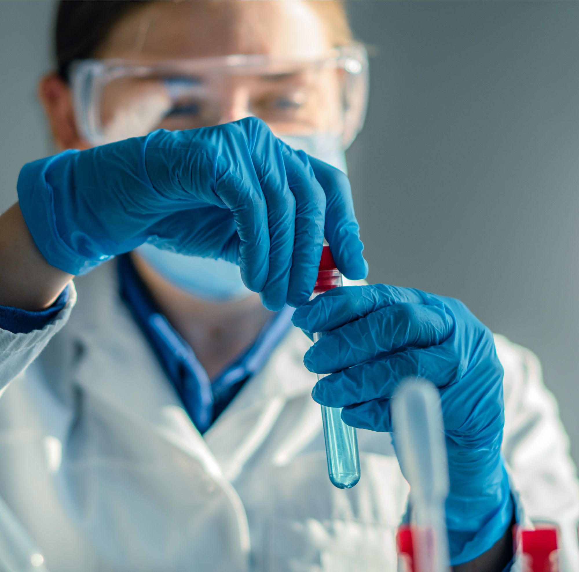 A technician seals a test tube containing blue liquid. 