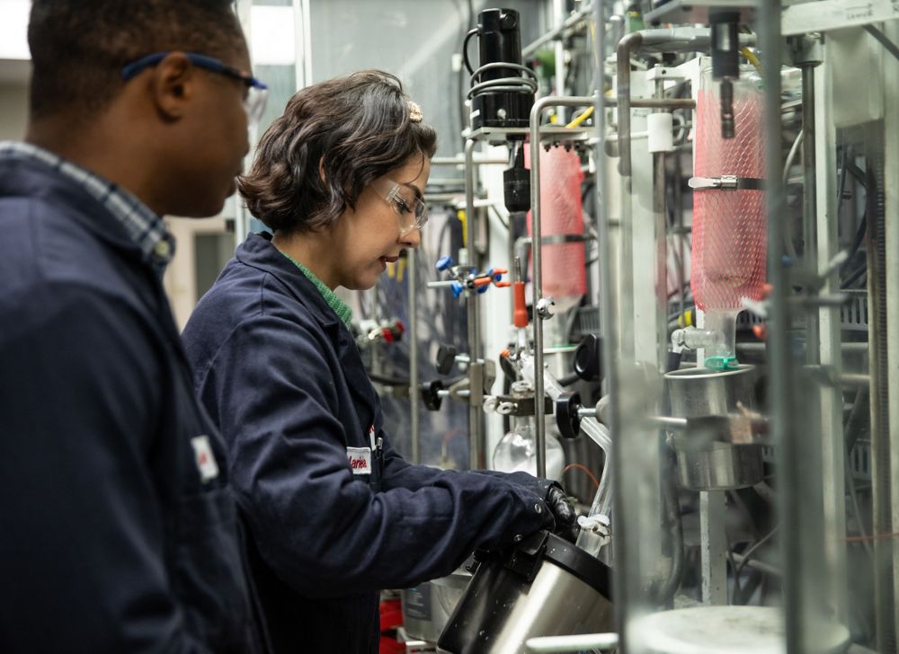 A woman and a man examine metal equipment. 